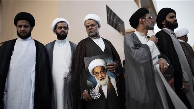 Bahraini Shia clerics attend a protest against the revocation of the citizenship of top Bahraini Shia cleric Sheikh Isa Qassim (portrait) near his house in the village of Diraz, west of the Bahraini capital, Manama, June ۲۰, ۲۰۱۶.