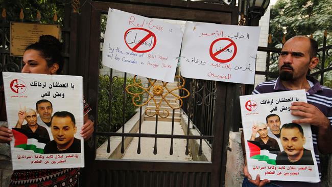 Palestinians hold posters of Palestinian prisoners on hunger strike in Israeli jails, including Bilal Kayed (R), as they demonstrate in front of the Red Cross headquarters in the occupied West Bank city of Ramallah
