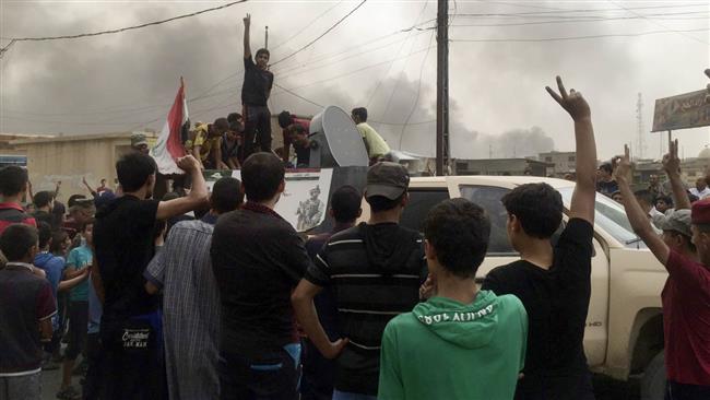 People celebrate as Iraqi security forces patrol Qayyarah, near Mosul