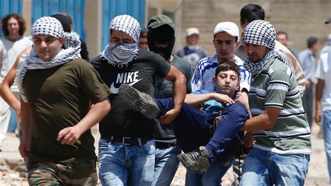 Palestinian protesters carry an injured teenager during clashes with Israeli forces
