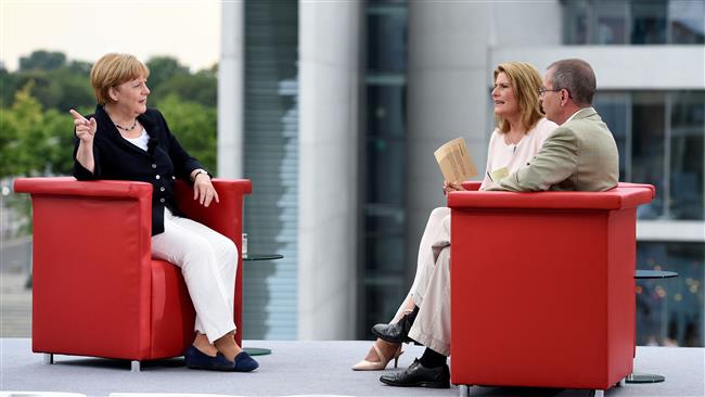 German Chancellor Angela Merkel (L) talks with TV journalists Tina Hassel and Thomas Baumann during her summer interview with German public TV chain ARD