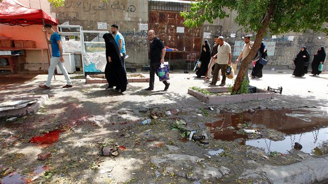 Iraqis walk at the site of a bombing near a checkpoint in the Kadhimiyah area, in northern Baghdad, Iraq, July 24, 2016.