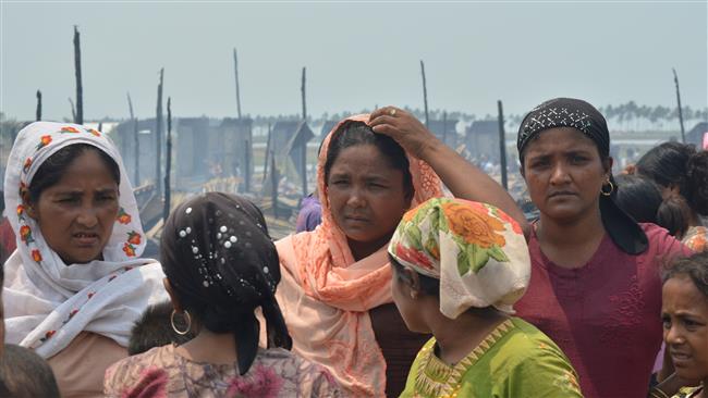 Rohingya Muslim residents gather and look on past their charred shelters following a fire that gutted Bawdupa camp near Sittwe, capital of Myanmar