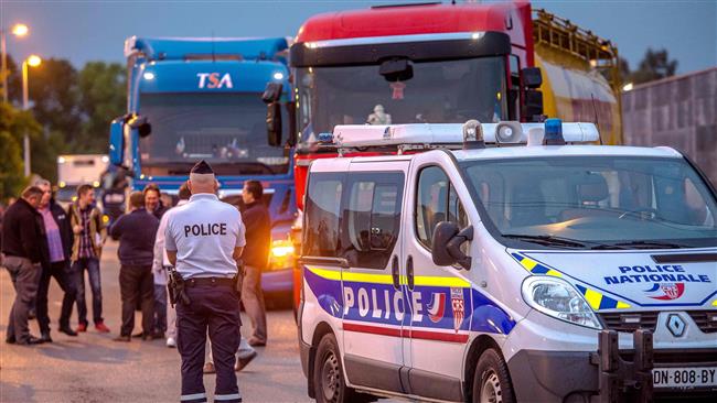 French police stand guard as truck drivers gather for a slow-down operation on the A16 highway on September 5, 2016. ©AFP