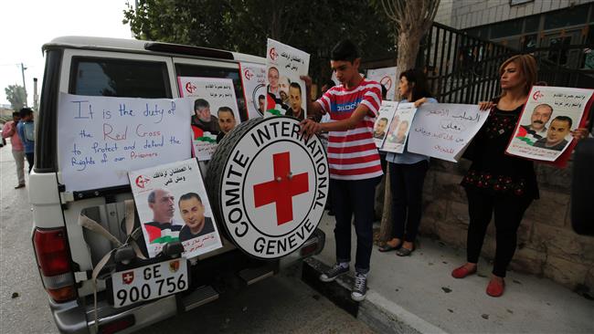 Palestinians cover a Red Cross vehicle with posters as they demonstrate in front of the Red Cross headquarters in the West Bank city of Ramallah in support of prisoners on hunger strike in Israeli jails on August 24, 2016. (AFP)