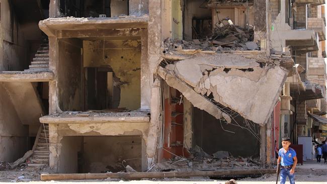 A Syrian boy carries a toy gun past a destroyed building in the northeastern Syrian city of Qamishli on September 13, 2016 as a truce brokered by Russia and the United States took effect the previous night. © AFP