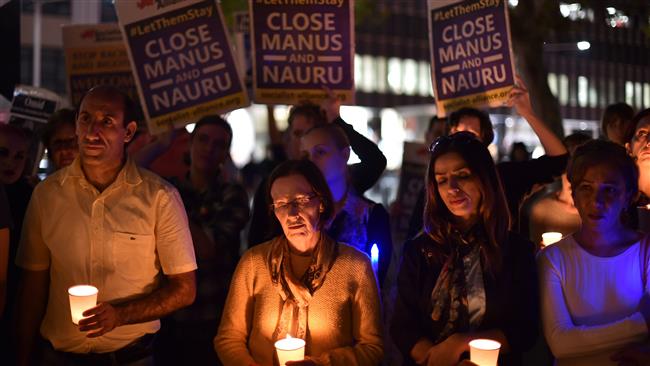 This image taken on April 30, 2016 in Sydney, Australia, shows rights activists taking part in a candle light vigil for refugees who set themselves on fire on the remote Pacific island of Nauru. (Photo by AFP)