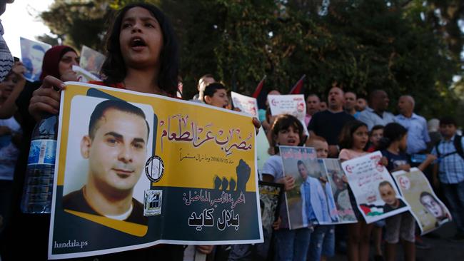 Palestinians hold posters with a picture of a Palestinian prisoner on hunger strike during a demonstration against his detention by the Israeli authorities, near the Red Cross offices in East Jerusalem al-Quds, August 3, 2016.(Photo by AFP)