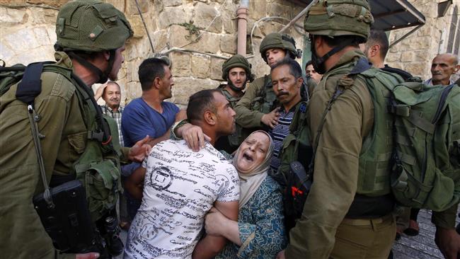 A Palestinian woman tries to prevent the arrest of a Palestinian man by Israeli soldiers in the southern occupied West Bank city of al-Khalil (Hebron) on September 20, 2016. (Photo by AFP)