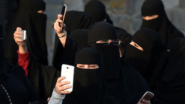 Saudi women use their mobile phones during the Janadriyah festival of heritage and culture held in the village of al-Thumama, near the capital city of Riyadh, on February 8, 2016. (Photo by AFP)