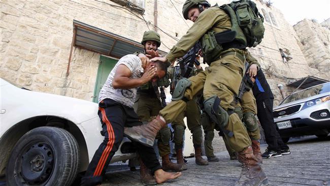 An Israeli soldier kicks a Palestinian man as the regime forces try to arrest him in the West Bank city of al-Khalil, aka Hebron, on September 20, 2016. (Photo by AFP)