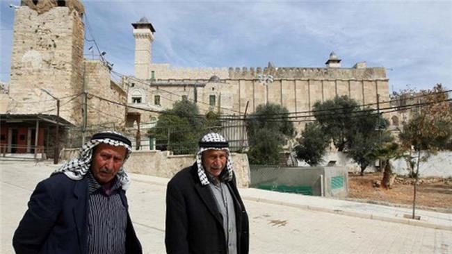 In this file photo, Palestinian men walk past the Ibrahimi Mosque in the heart of the occupied West Bank city of al-Khalil (Hebron).