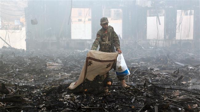A Yemeni man covers a charred body amid the rubble of a destroyed building following Saudi airstrikes on Sana