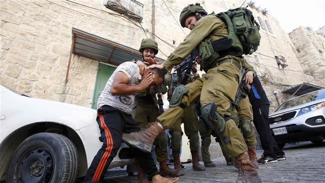 An Israeli soldier kicks a Palestinian man as troops try to arrest him in the southern West Bank city of al-Khalil (Hebron) on September 20, 2016. (Photo by AFP)