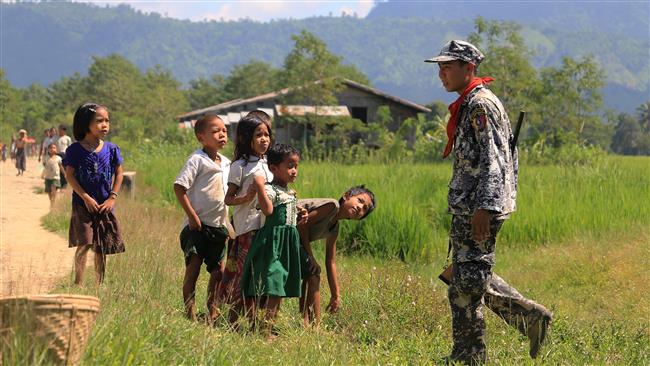 In this photograph taken on October 21, 2016, children look at a policeman in Laung Don in Rakhine State as a security operation continues following an alleged raid on government soldiers. (Photo by AFP)