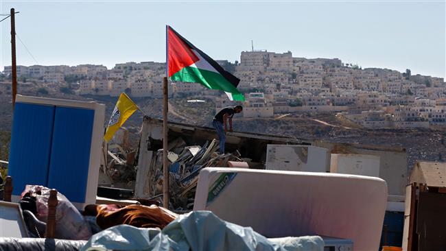 A Palestinian man searches through his belongings after his family home was demolished by Israeli workers in the East Jerusalem al-Quds neighborhood of Beit Hanina, near the Israeli settlement of Ramat Shlomo (background), on October 26, 2016. (Photo by AFP)