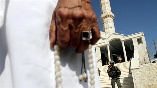 A Palestinian man holds prayer beads as he stands near an Israeli officer outside a damaged mosque in the village of Jaba near Ramallah in the Israeli-occupied West Bank. (File photo)