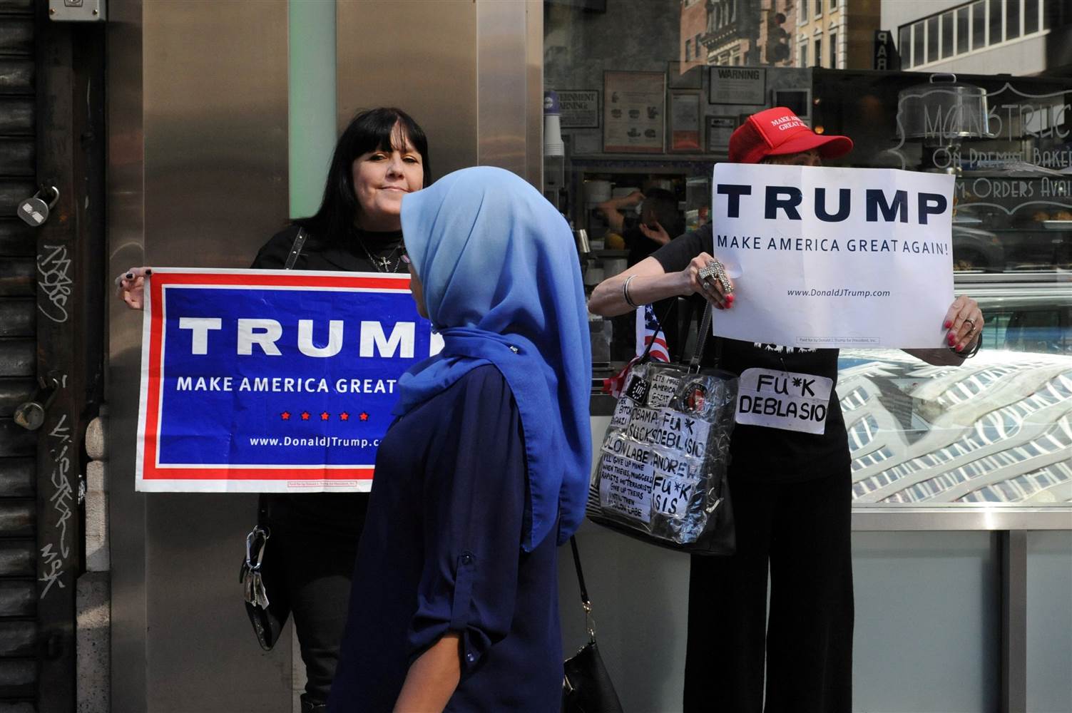 A woman wearing a Muslim headscarf walks past people holding Donald Trump signs before the annual Muslim Day Parade in the Manhattan on Sept. 25. Stephanie Keith / Reuters