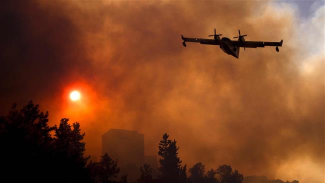 An Israeli firefighter plane helps extinguish a fire in Haifa on November 24, 2016. (Photo by AFP)