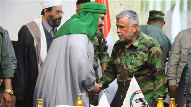 The file picture shows Abdul-Qadir al-Alousi, who chairs the Council of Scholars of Baghdad (L), shaking hands with Hadi al-Ameri, the commander of the Shia-majority Popular Mobilization Units, or Hashd al-Sha’abi volunteer force.