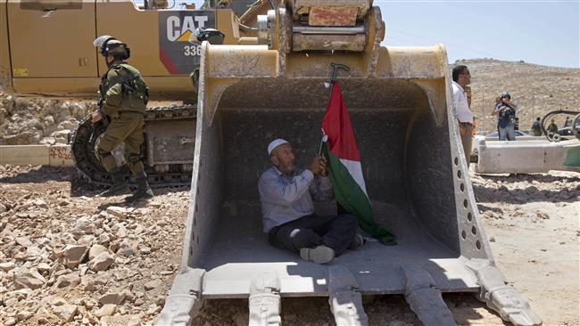 A Palestinian man tries to stop work by an Israeli bulldozer during a protest outside the village of Deir Qaddis, near the West Bank city of Ramallah, on July 13, 2016. (Photo by AP)