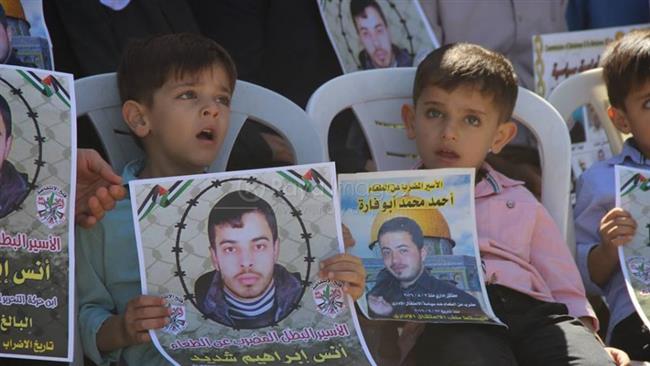 In this file photo, Palestinian children hold the portraits of Palestinian hunger strikers Anas Ibrahim Shadid (L) and Ahmad Abu Farah during a protest in the occupied West Bank.