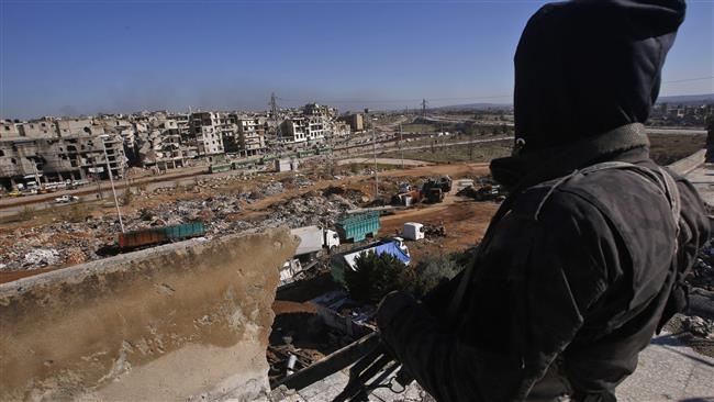 A member of the Syrian pro-government forces watches buses in the distance during an evacuation operation of militants and their families from the eastern neighborhoods of Aleppo on December 15, 2016.