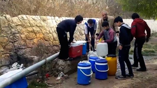 Syrian residents fill up buckets with spring water from a pipe on the side of a road in the capital Damascus. (Photo by AP)