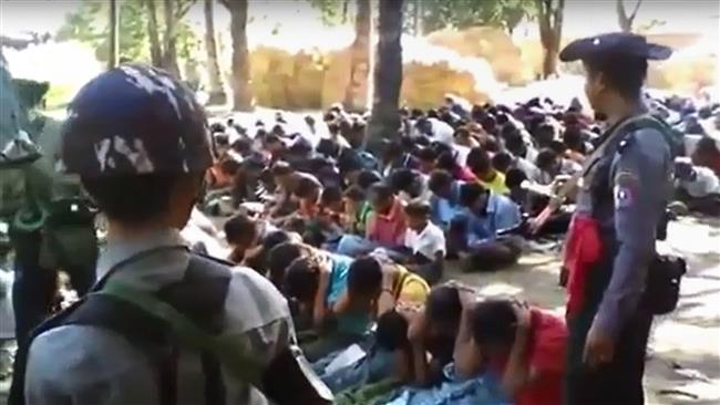 This screen grab taken on January 4, 2017, from a YouTube video shows policemen standing guard around Rohingya Muslim villagers seated on the ground in Kotankauk during a police area clearance operation on November 5, 2016. (Via AFP)