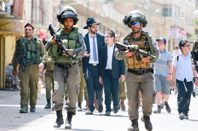 Israeli soldiers escort Jewish settlers in the occupied West Bank town of Hebron