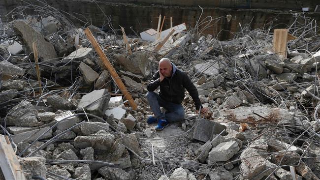 A Palestinian man sits amid the rubble of a house that was demolished by Israeli military bulldozers in the East Jerusalem al-Quds neighborhood of Beit Hanina on January 4, 2017. (Photo by AFP)