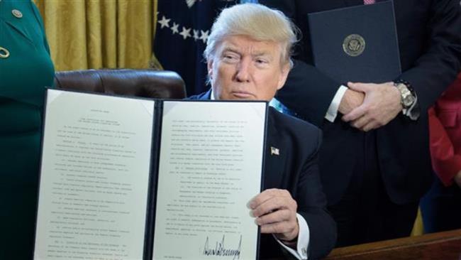 US President Donald Trump shows an executive order directing the Treasury Secretary to review the Dodd-Frank financial oversight law in the Oval Office of the White House on February 3, 2017 in Washington. (Photo by AFP)