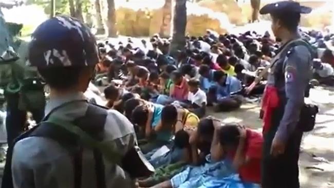 This screen grab, taken on January 4, 2017, shows policemen standing guard around Rohingya minority villagers seated on the ground in the village of Kotankauk on November 5, 2016. (By AFP)