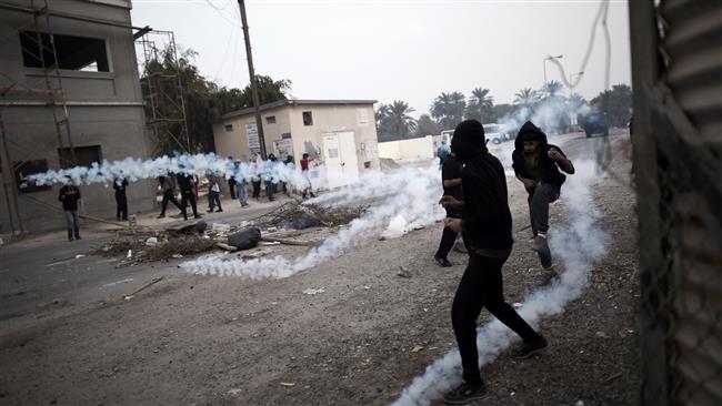 The photo taken on February 13, 2015 shows Bahraini protesters taking cover from tear gas during clashes with police following a demonstration on February 13, 2015, to mark the fourth anniversary of the Bahraini uprising, in the village of Bilad al-Qadim on the outskirts of the capital, Manama. (Photo by AFP)
