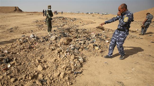 Iraqi forces point at a mass grave they discovered in the Hamam al-Alil area, south of Mosul on November 7, 2016. (Photo by AFP)