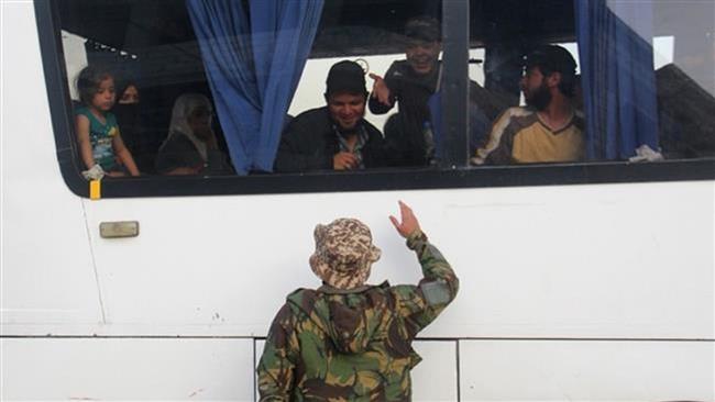 A militant greets people in a convoy of buses and ambulances transporting civilians and militants from the towns of Zabadani and Madaya on the outskirts of the city of Idlib in northwestern Syria on April 21, 2016. (Photo by AFP)