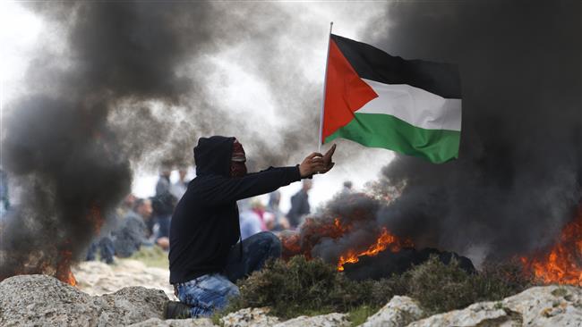 A demonstrator holds a Palestinian flag as Israeli forces clash with Palestinians protesting against a planned new settlement near Mughayyir village close to the West Bank city of Ramallah on March 24, 2017. (Photo by AP)