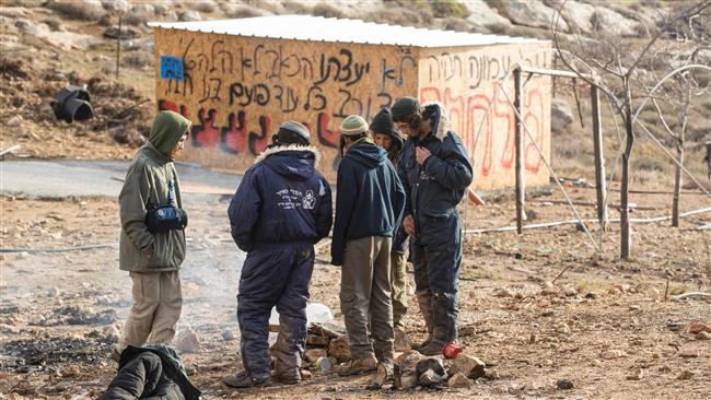 Israeli settlers stay around a fire in the settlement outpost of Amona on December 15, 2016. (Photo by AFP)