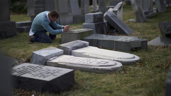 A man photographs Jewish tombstones laying vandalized at Mount Carmel Cemetery February 27, 2017 in Philadelphia, Pennsylvania. (Getty Images)