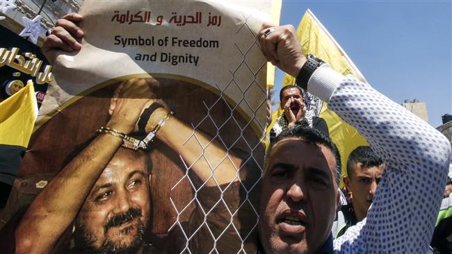 A man holds a photo of prominent Palestinian prisoner Marwan Barghouti calling for his release during a rally supporting those detained in Israeli jails after hundreds of them launched a hunger strike in the occupied West Bank town of al-Khalil (Hebron) on April 17, 2017. (Photo by AFP)