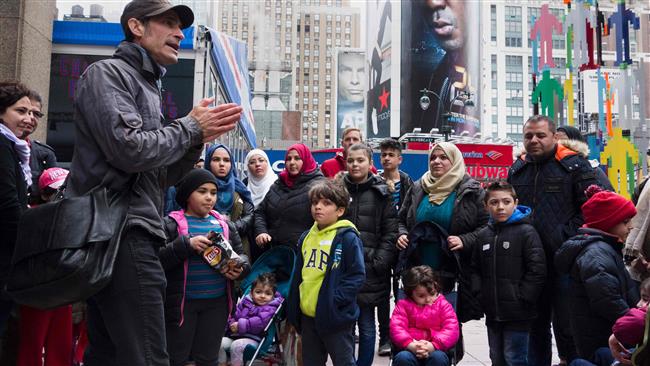 Tour guide Luke Miller talks to a group of mostly Syrian but some Iraqi refugee families gathered outside Madison Square Garden for a tour of Manhattan in New York, on April 21, 2017. (Photo by AFP)