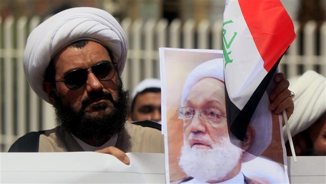 An Iraqi Shia cleric holds a picture of top Bahraini cleric Sheikh Isa Qassim during a demonstration in front of the Bahraini consulate in Najaf, Iraq, on May 24, 2017. (Photo by AFP)