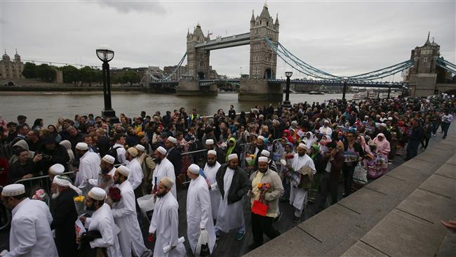 Members of the Dawoodi Bohra Muslim community (in white) join others as they bow their heads during a vigil at Potters Fields Park in London on June 5, 2017 to commemorate the victims of the terror attack on London Bridge and at Borough Market that killed seven people on June 3. (Photo by AFP)