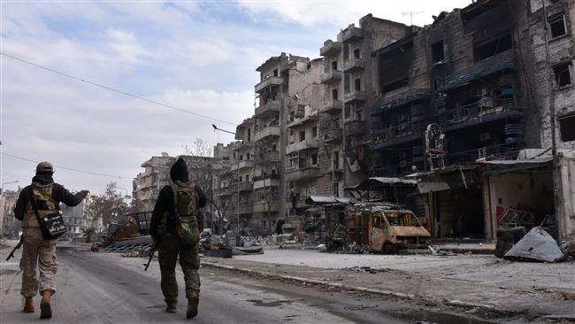 Syrian government forces walk past destroyed buildings in the former militant-held Ansari district in the city of Aleppo on December 23, 2016. (Photo by AFP)