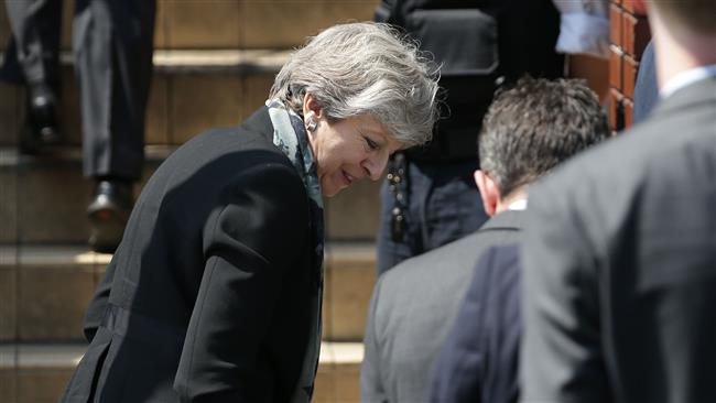 British Prime Minister Theresa May reacts as her shoe falls off whilst arriving at Finsbury Park Mosque in the Finsbury Park area of north London, June 19, 2017. (Photo by AFP)