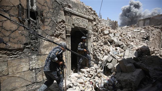 Members of the Iraqi federal police hold position during an armed exchange as smoke billows in the background while advancing through the Old City of Mosul on June 28, 2017, as the offensive continues to retake the last district held by Daesh terrorists.