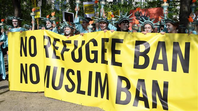Protesters wearing Statue of Liberty costumes hold a banner reading