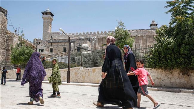 A picture taken on July 7, 2017 shows Palestinians walking by outside the Ibrahimi Mosque from the Palestinian side in the heart of the divided city of al-Khalil (Hebron) in the southern West Bank. (By AFP)
