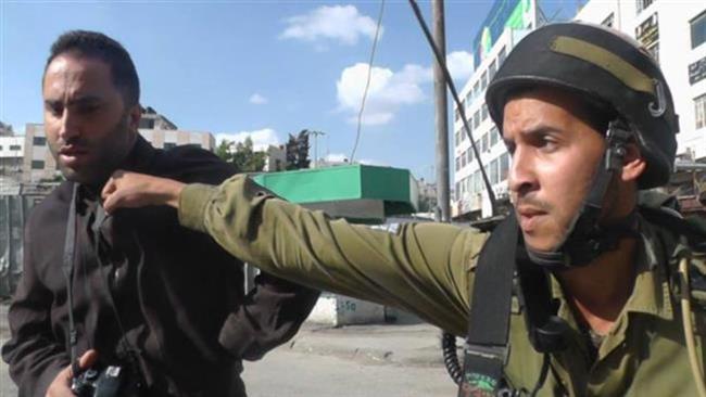 In this file photo, an Israeli trooper punches Palestinian human rights activist Issa Amro in the occupied southern West Bank city of al-Khalil (Hebron).