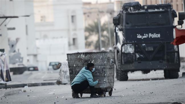 This AFP file photo taken on January 2, 2015 shows a Bahraini protester taking cover behind a garbage container during clashes with riot police following a demonstration on January 2, 2015.